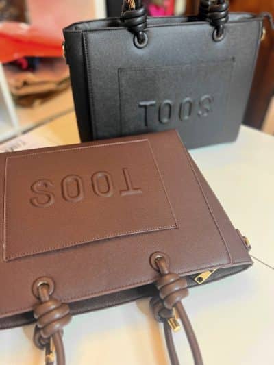 Erlebe die Toos Handtasche: Wählen Sie Ihr Lieblingsmodell in elegantem Schwarz oder warmem Braun mit modernem Prägelogo.