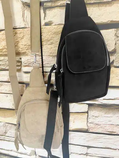 Erlebe modernen Style: Die Sling Crossover Bag in Schwarz und Tan wartet an der Wand darauf, dein Outfit zu vervollständigen.
