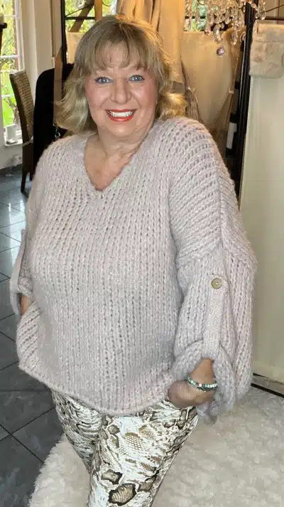 Fühl dich wohl in deinem Kuschel Pulli - du stehst entspannt am Fenster, stylisch mit gemusterten Hosen und einem Lächeln.