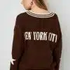 Zieh den Varsity Star Pulli an - braun, mit "New York City"-Backprint und Stern am Ärmel - zu hellblauen Jeans für deinen coolen Style.