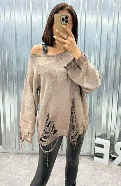 Du rockst den Look: Zerrissener beigefarbener Sweater, schwarze Leggings - selfie-tauglich vor metallischer Kulisse.
