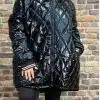 Präsentiere dich stylisch: Im Glossy Oversize Coat, schwarzen Leggings und weißen Sneakern rockst du die Backsteinwand!.