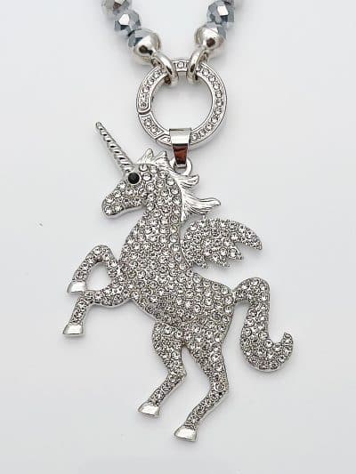 Entdecke deinen Jahreszeiten Wechsel Anhänger: Ein silbernes Einhorn mit funkelnden Steinen und Flügeln an moderner Perlenkette.