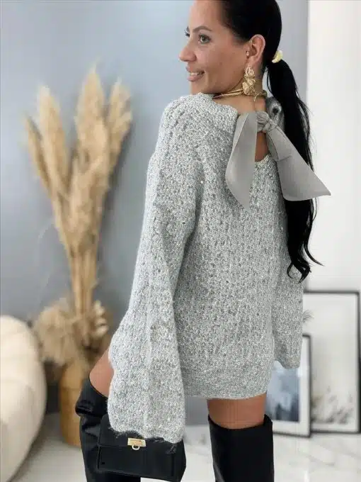 Du trägst den Miss Starry Longpullover in Grau mit Schleife, stylischen Boots und goldenen Ohrringen - trendy neben Pampasgras.