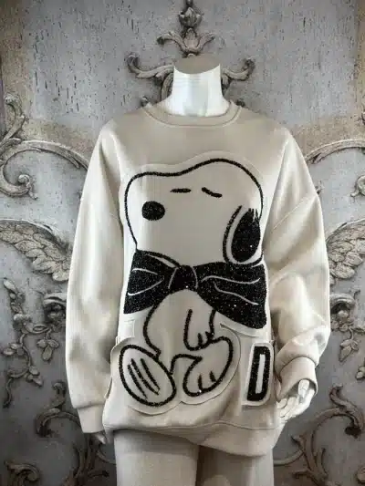 Entdecke deinen neuen Lieblingspulli: Cremefarbener Sweater mit Snoopy-Print und funkelnder Glitzer-Schleife - modern, stylish, trendy!.