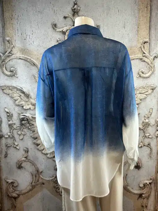 Entdecke die Crystal Ombre Bluse: Dein Fashion-Highlight mit blau-weißem Farbverlauf, perfekt inszeniert vor edlem Hintergrund.