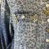 Entdecke deinen Style: Denim-Shirt mit wildem Leo-Print und funkelnden Schmucksteinen auf deiner Brusttasche.