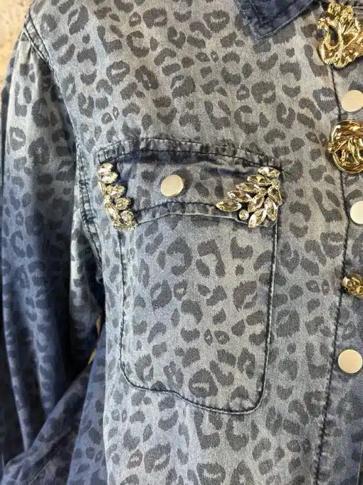 Entdecke deinen Style: Denim-Shirt mit wildem Leo-Print und funkelnden Schmucksteinen auf deiner Brusttasche.