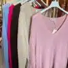 Entdecke deinen Style: Sechs bunte Pullover auf weißen Bügeln, die vorne pinke, frische Farben warten auf dich!.