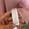 Du hältst einen stylishen pinken Pullover in der Hand - das Label verrät dir Materialmix und smarte Pflegehinweise.