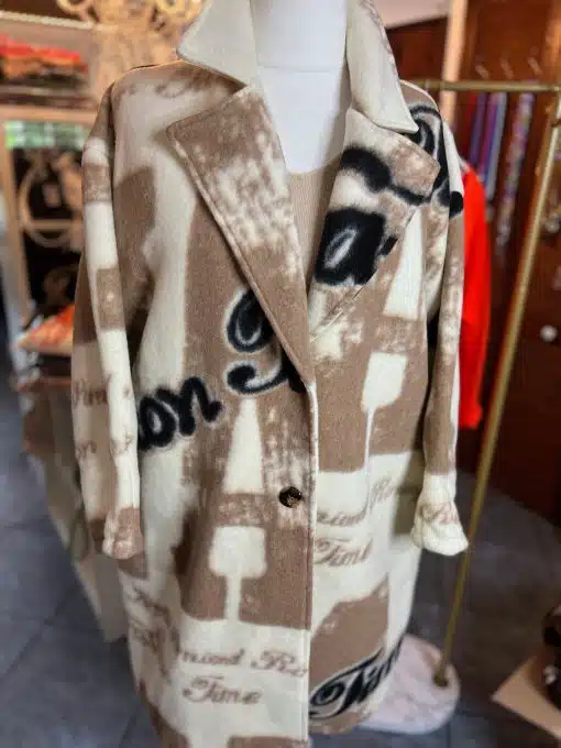 Mit diesem Fashion Statement Mantel setzt du ein Statement: Schwarze Schrift und abstraktes Muster in Beige und Creme sorgen für Wow-Effekt.