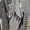 Entdecke deinen Look: Zwei stylische Ethno-Ponchos mit Fransen warten vor trendigem Steinmuster darauf, von dir getragen zu werden!.