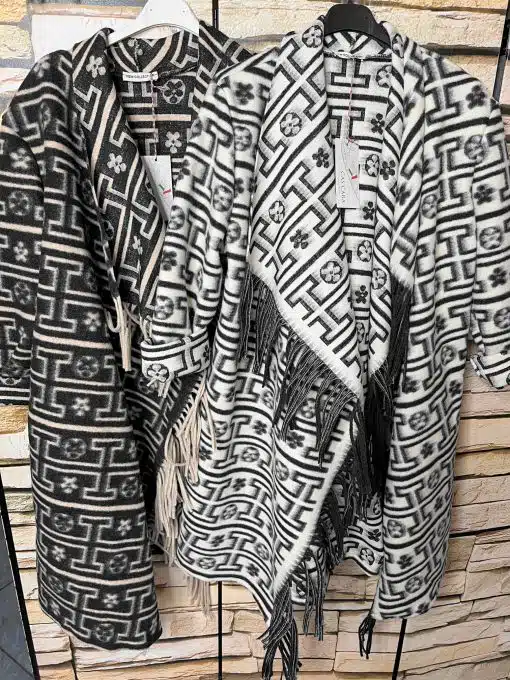 Entdecke deinen Look: Zwei stylische Ethno-Ponchos mit Fransen warten vor trendigem Steinmuster darauf, von dir getragen zu werden!.