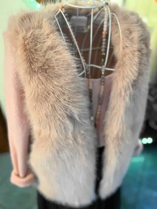 Du trägst die Mattea Fellweste aus flauschigem Kunstfell über einem pinken Top - perfekt abgerundet mit langen Trend-Perlenketten.