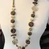 Entdecke deine neue Golden Jungle Statementkette - mit braunen, goldenen und cremefarbenen Perlen, modern präsentiert am Mannequin.
