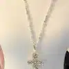 Setzen Sie ein Statement mit der Eternal Shine Kette - funkelndes Kreuz, edle Perlen, präsentiert auf einer stilvollen Büste.