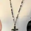 Setzen Sie mit der Eternal Shine Statementkette ein Fashion-Statement - schwarze Perlen, markantes Kreuz, präsentiert am weißen Torso.