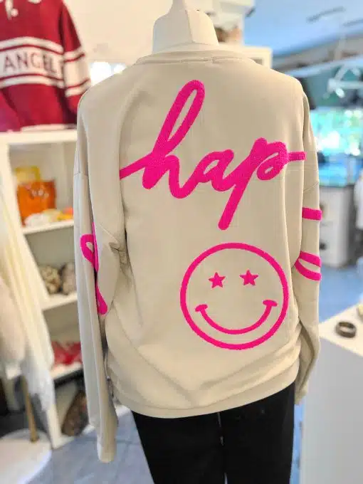 Hol dir das stylische "Be Happy" Sweatshirt in Beige - hinten mit "hap-" und einem pinken Smiley mit Sternaugen als Eyecatcher!.