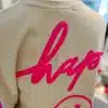 Hol dir das moderne Be Happy Sweatshirt in Beige mit knalligem pinken "hap"-Schriftzug und coolem Smiley mit Sternaugen auf dem Rücken!.