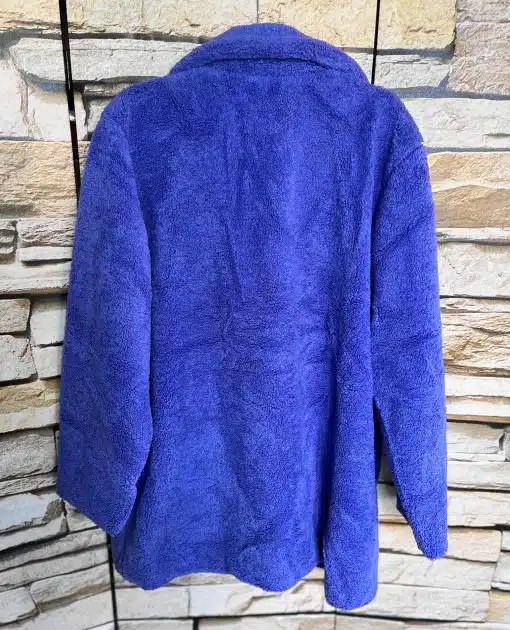 Erlebe deinen Style neu: Deine blaue, flauschige Lieblingsjacke setzt vor rauer Steinwand ein trendiges Statement.