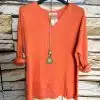 Zieh dir das angesagte orange "Basic Deluxe - Shirt mit Kette" an: stylisch, modern, ein echter Eyecatcher vor Steinwand!.
