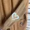 Zeig deinen Style: Der braune Strickfäustling mit weißem Herz setzt an deinem Herzstück-Cardigan ein trendiges Statement.