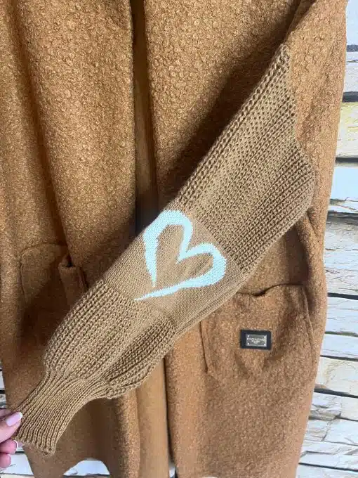 Zeig deinen Style: Der braune Strickfäustling mit weißem Herz setzt an deinem Herzstück-Cardigan ein trendiges Statement.