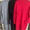 Entdecke deinen neuen Look: Drei trendige Strickkleider mit langen Ärmeln in Grau, Schwarz und Rot vor Steinmuster.