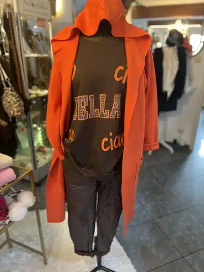 Entdecke deinen Look: Im stylishen Orangenmantel, "bella ciao"-Shirt und schwarzen Pants von Zwillingsherz strahlst du modern.