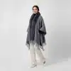 Trage den grauen Jolina Poncho Schal mit Fell und Fransen zu weißen Hosen und Heels - dein moderner Look für selbstbewusste Auftritte!.