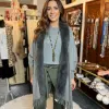 Erlebe deinen Style: Im grauen Jolina Poncho Schal, grüner Hose und Statementkette strahlst du zwischen trendigen Accessoires.