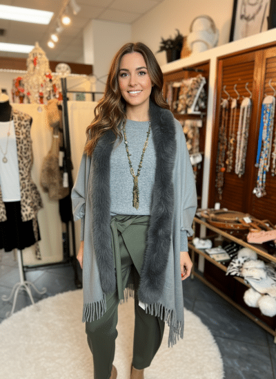 Erlebe deinen Style: Im grauen Jolina Poncho Schal, grüner Hose und Statementkette strahlst du zwischen trendigen Accessoires.