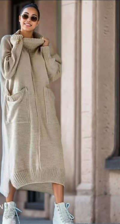 Erlebe, wie du im langen, beigen Soft & Snug Strickkleid mit Taschen, Sonnenbrille und weißen Sneakern stilvoll strahlst.