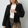 Entdecke deinen Look: Du trägst den schwarzen Trenchcoat und präsentierst die Wild Whisper Tasche im trendigen Leo-Design mit Goldkette.