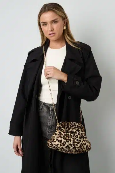 Entdecke deinen Look: Du trägst den schwarzen Trenchcoat und präsentierst die Wild Whisper Tasche im trendigen Leo-Design mit Goldkette.