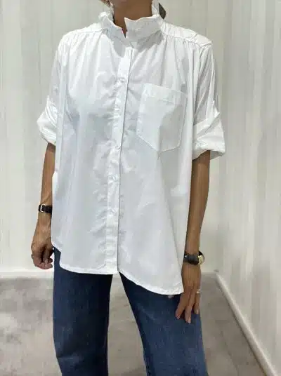 Du trägst die Everyday Cotton Blouse: lässig-weiße Baumwolle, modern gekrempelte Ärmel, kombiniert mit coolen Blue Jeans.