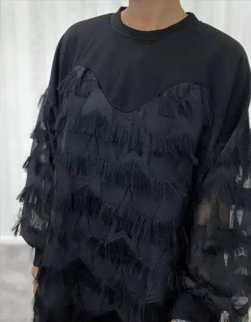Du trägst ein angesagtes schwarzes Top mit transparenten Ärmeln und trendigen Fransen-Sternmustern als stylishes Statement.