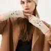 Du trägst einen schicken beigen Mantel, eine cremefarbene Schmuck-Beanie und passende Fingerhandschuhe - dein moderner Look.