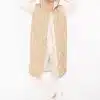 Du trägst eine lange beige Steppweste über weißem Outfit, lächelst und hältst cool die Kapuze - bereit für deinen modernen Look.