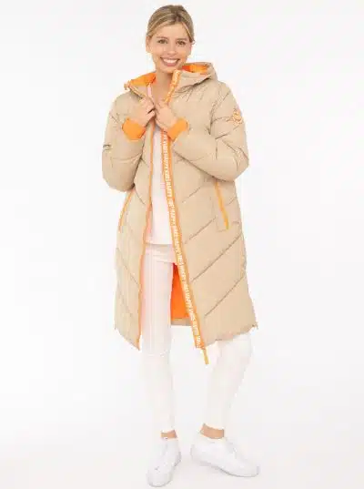 Entdecke deinen Style mit dem beigen "Happy Vibes" Steppmantel, coolen orangen Akzenten, weißen Pants und Sneakern.