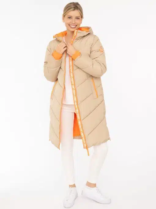 Entdecke deinen Style mit dem beigen "Happy Vibes" Steppmantel, coolen orangen Akzenten, weißen Pants und Sneakern.