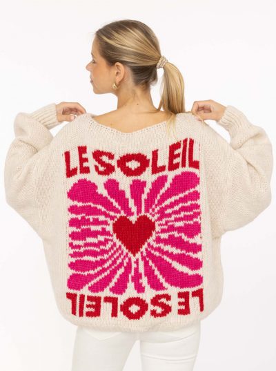 Du trägst einen cremefarbenen Pullover mit auffälligem pink-rotem Sunburst und stylischem "LE SOLEIL"-Schriftzug auf dem Rücken.