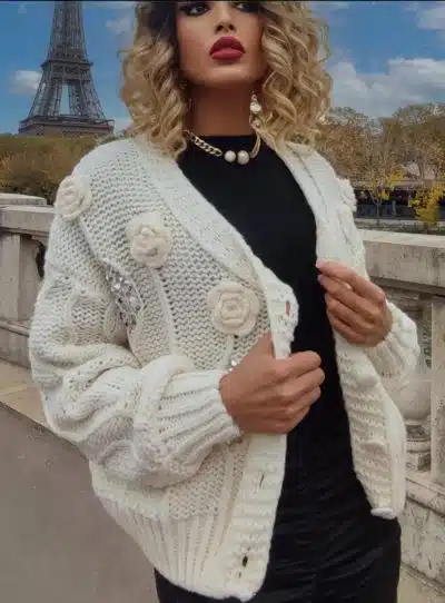Du spazierst im trendigen weißen Strickpullover mit Blumen-Details am Eiffelturm und genießt das Flair von Paris.