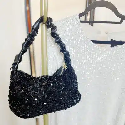 Entdecke deine glamouröse schwarze Paillettentasche - perfekt kombiniert mit dem funkelnden weißen Paillettenkleid am Ständer!.