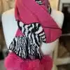 Mit dem Wildlook Schal wirst du zum Trendsetter: Weicher Strick, Animal-Print und pinke Kunstfell-Bommel, stylisch präsentiert.