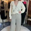 Erlebe das Funkeln: Du trägst eine cremefarbene Strickjacke und Midnight Sparkle Hose im stilvollen Vintage-Boutique-Flair.