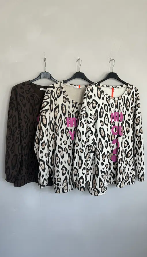 Entdecke deinen neuen Style: ARE YOU OK Sweatshirts im Leo-Look mit pinker Schrift, stylisch auf schwarzen Bügeln präsentiert.