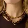 Setze ein Statement mit deinem Look: Trage zwei angesagte Ketten, Gold-Perlen und auffällige Tortoise-Beads auf dunklem Top.