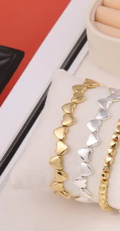 Entdecke goldene und silberne Herz-Armbänder auf weißem Kissen - Dein perfektes Schmuck-Highlight im stilvollen Tray!.