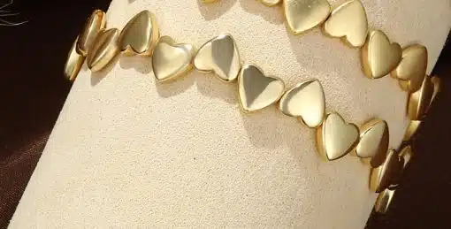 Entdecken Sie diese modernen Goldarmbänder mit herzförmigen Gliedern - perfekt präsentiert auf einem edlen, beigen Display.